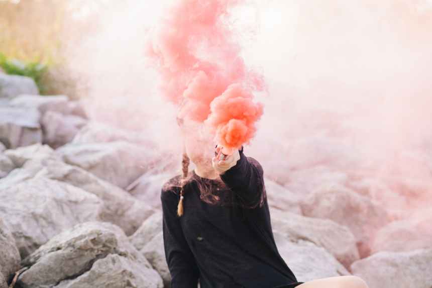 woman holding color smoke grenade